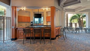 A kitchen with a bar area, including a counter and bar stools, and a patio with outdoor seating. - Paradise, a Hilton Grand Vacations Club near the Las Vegas Convention Center (Las Vegas)