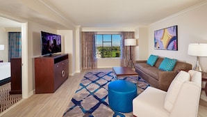 A hotel room with a TV, a sofa, a coffee table, a lamp, and a view of the outdoors. - Paradise, a Hilton Grand Vacations Club near the Las Vegas Convention Center (Las Vegas)