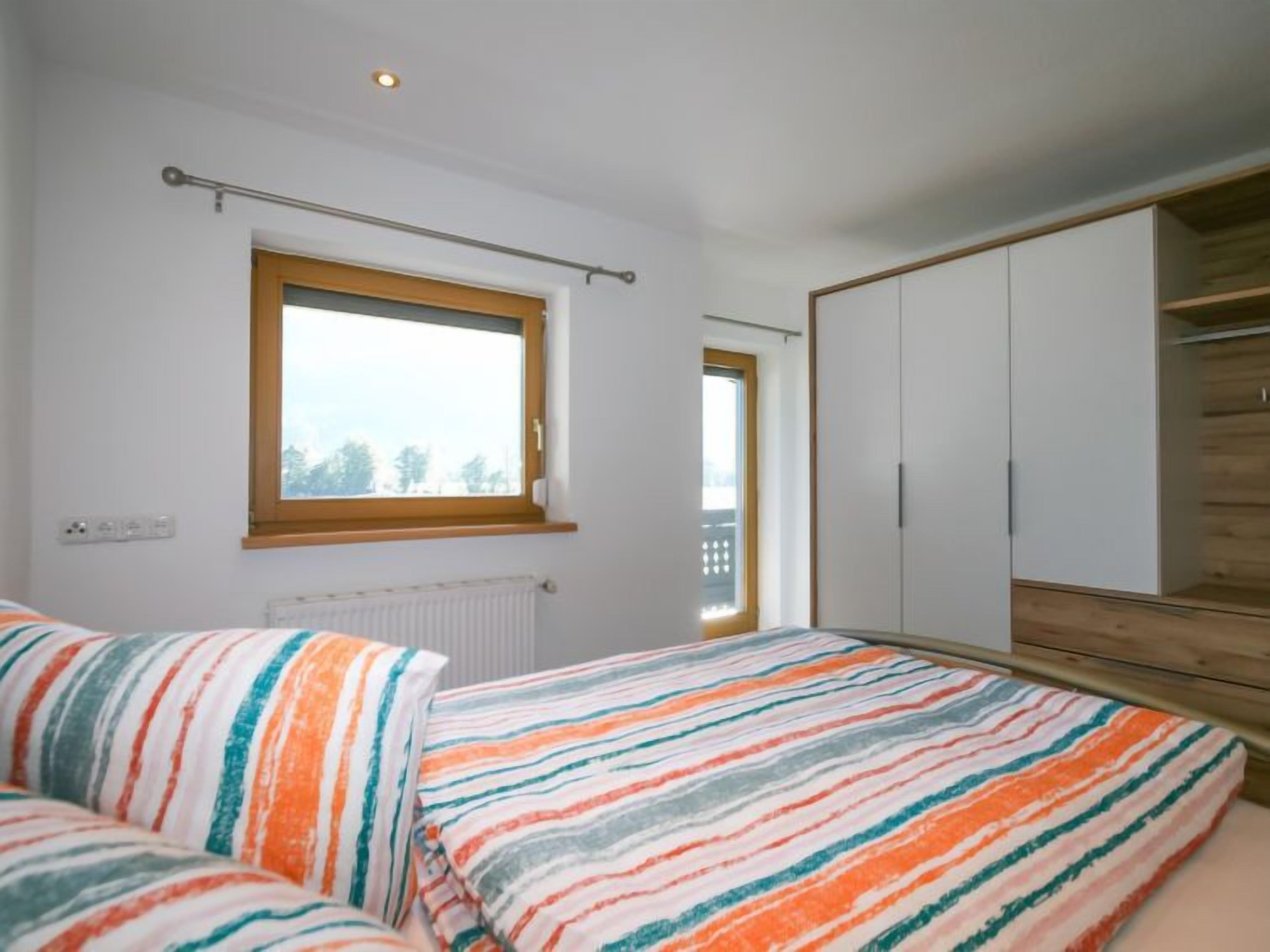 A bedroom with a bed, a window, a radiator, and a wardrobe.