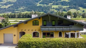 A yellow house with a balcony, surrounded by green hills and trees. - Der Pinsler by Interhome (Fügen)