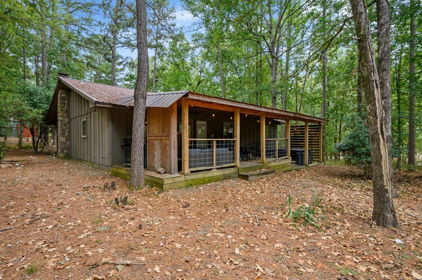 A rustic cabin with a porch, surrounded by trees.