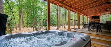 Un jacuzzi bajo una terraza de madera con vistas al bosque.