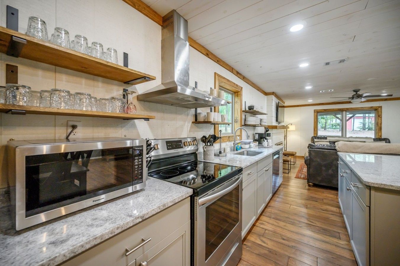 Een moderne keuken met roestvrijstalen apparatuur, houten planken en een groot raam.