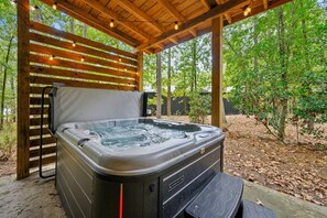A hot tub under a wooden pergola in a wooded area. - EZ Ridge Retreat | Rustic Broken Bow Lake Cabin with Hot Tub, Fire Pit, Grill & Pets (Hochatown)