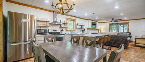 Una cocina moderna con electrodomésticos de acero inoxidable, una zona de comedor con sillas de madera y un ventilador de techo.
