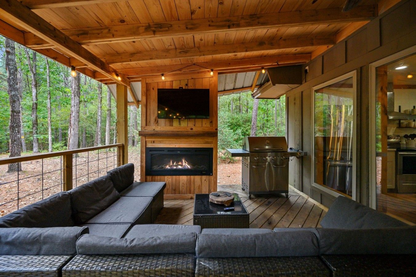 A covered outdoor area with a fireplace, a grill, and a seating area with a sofa and a table.