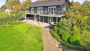 A modern two-story house with a balcony, a stone pathway, and surrounding greenery. - "Berta" - 70m to the fjord by Interhome (Roslev)