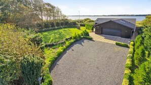 A modern house with a garage, surrounded by a well-maintained lawn and dense trees. - "Berta" - 70m to the fjord by Interhome (Roslev)