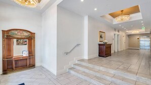 Un vestíbulo amplio con una imponente escalera, una recepción y un candelabro.