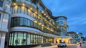 Un hôtel moderne doté d’une façade incurvée, de grandes fenêtres et d’un éclairage extérieur.