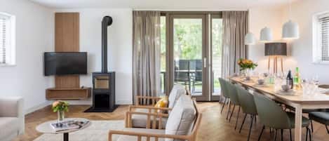 A modern living room with a fireplace, a dining area, and a TV mounted on the wall.