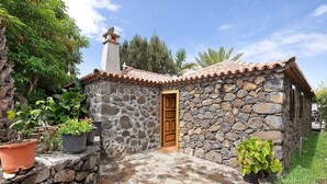 Un bâtiment en pierre avec un toit en tuiles, une porte en bois et des plantes en pot.