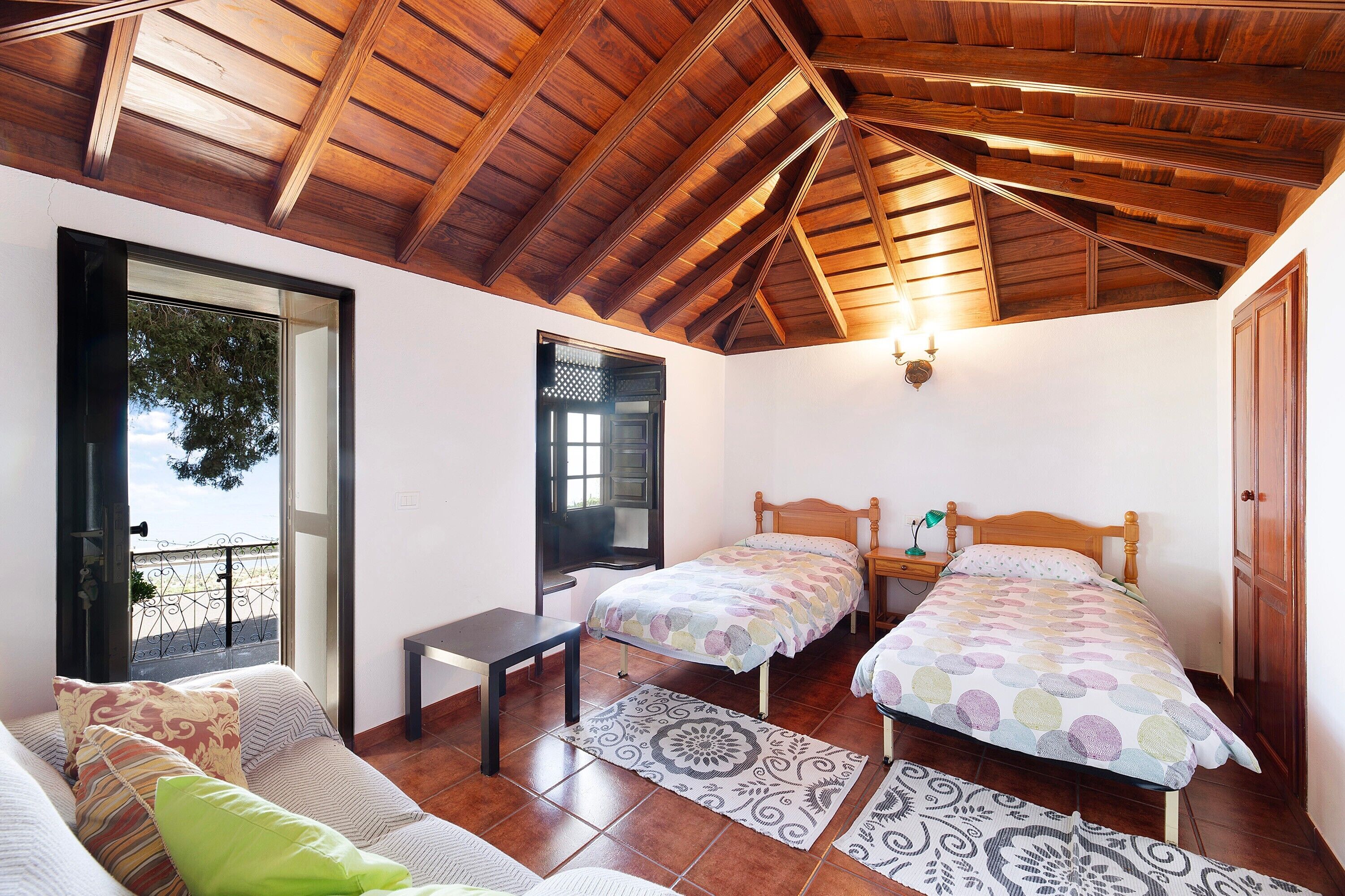 Una habitación con techo de madera, dos camas, un sofá y una ventana con vistas.