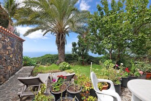 Une terrasse avec des meubles d’extérieur, des plantes en pot et un mur en pierre.