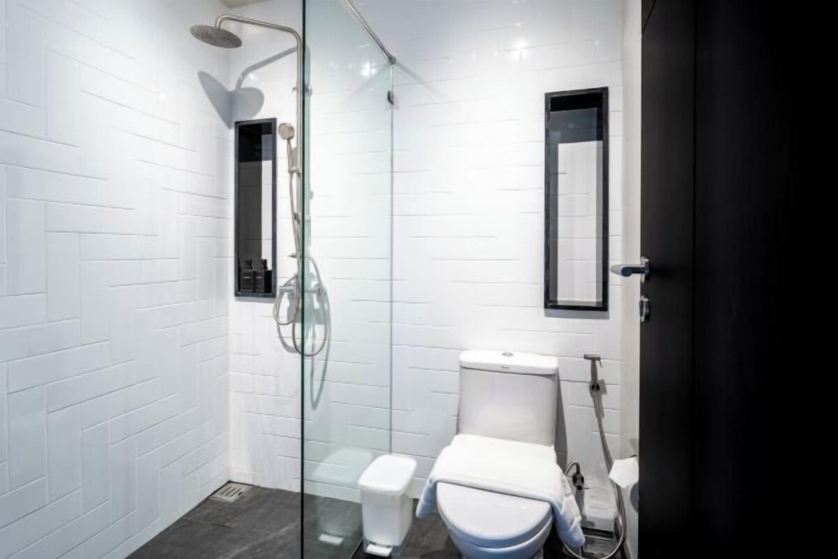 Een moderne badkamer met een douchecabine van glas, een wit toilet en een spiegel met een zwart frame.