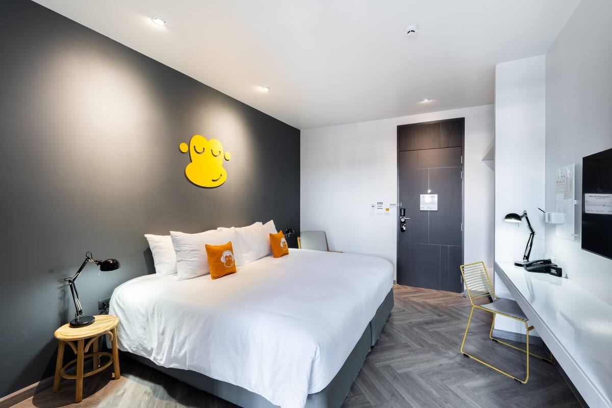 Ein modernes Hotelzimmer mit einem großen Bett, einem Schreibtisch und einem Sessel.