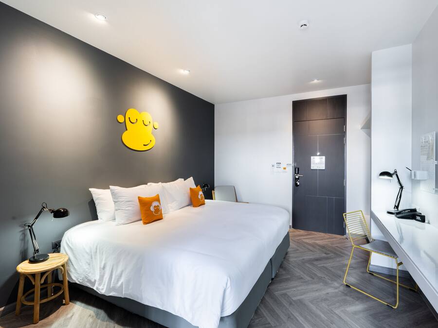 Ein modernes Hotelzimmer mit einem großen Bett, einem Schreibtisch und einem Sessel.