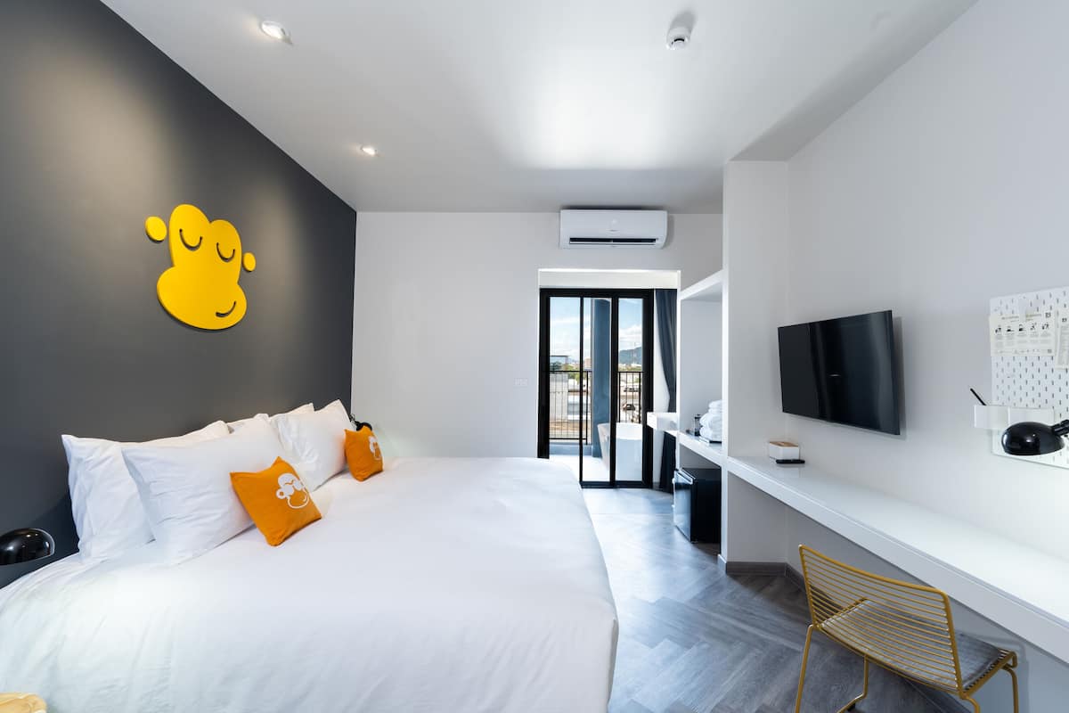 Ein modernes Hotelzimmer mit einem großen Bett, einem Fernseher und einem Schreibtisch.
