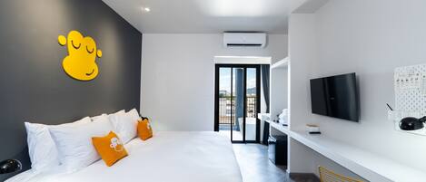 A modern hotel room with a large bed, a TV, and a desk.