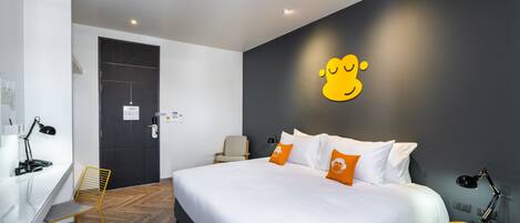 A modern hotel room with a large bed, a desk, and a chair.