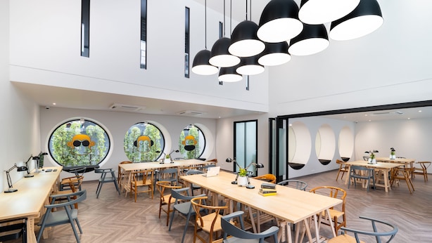 Une salle de réunion moderne, dotée de tables rondes, de chaises et de grandes fenêtres offrant une vue circulaire.