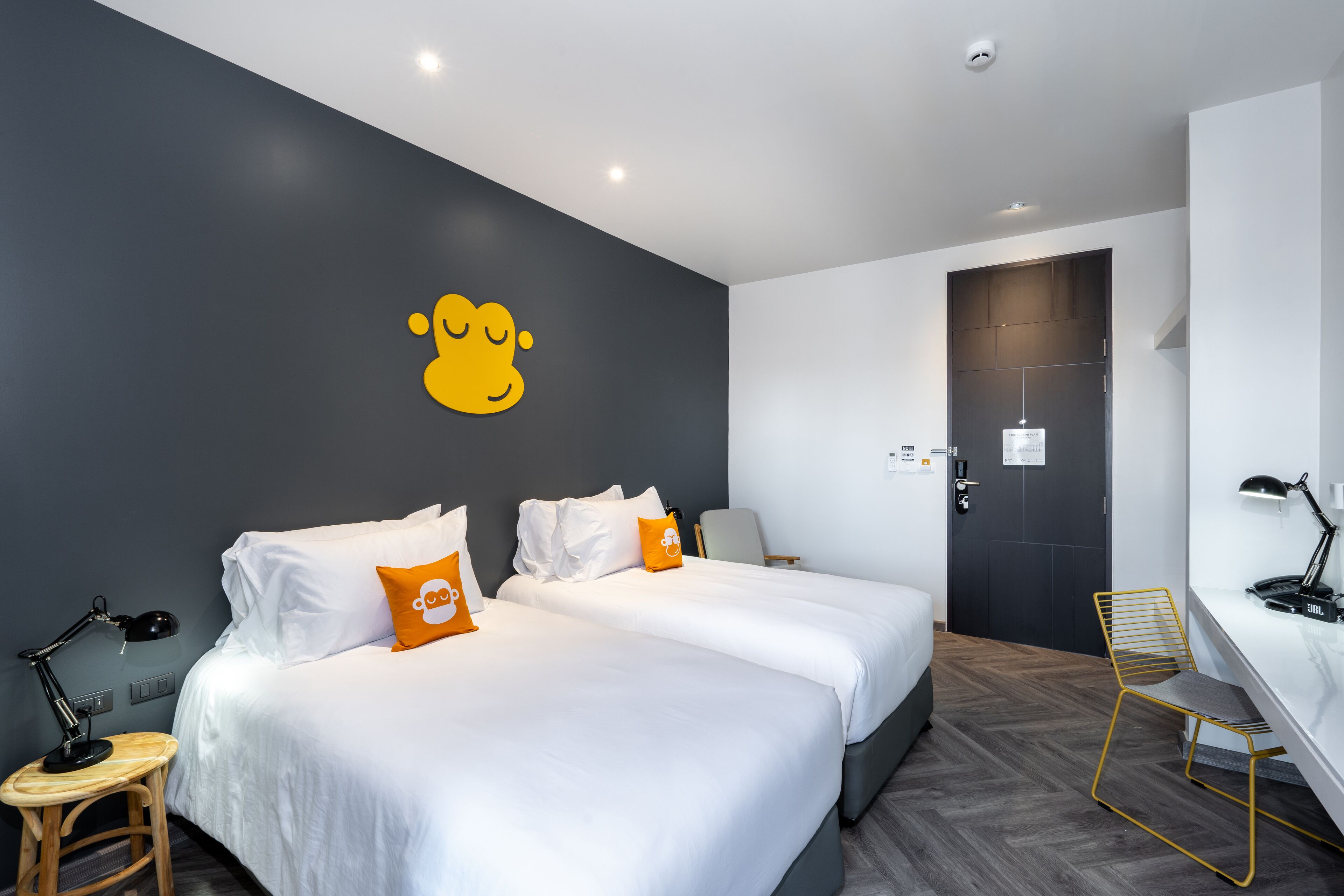 Une chambre d’hôtel moderne avec deux lits, un bureau et une chaise.
