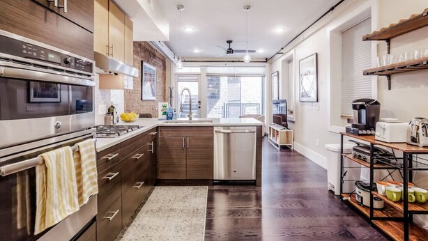 Una cocina moderna con electrodomésticos de acero inoxidable, armarios de madera y una isla central.