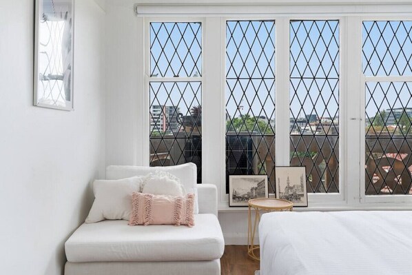 Un dormitorio con un sofá blanco, una mesita redonda y una cama.