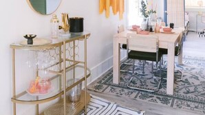 A dining area with a table set for four, a chandelier, and a mirror on the wall.