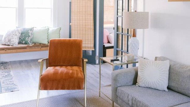 A living room with a ceiling fan, a sofa, a chair, a lamp, and a bookshelf.