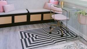A room with a built-in bench along the window, a patterned rug, and a floor lamp.