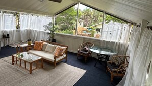 A covered outdoor seating area with a sofa, chairs, and a table. - Tree Top Getaway- Sleeps 4 (Gulfport)