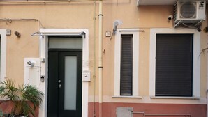 A building with a black door, a small porch, and a window with a shutter. - PALMHOUSE Salerno center with jacuzzi, separate entrance near Metro. (Salerno)