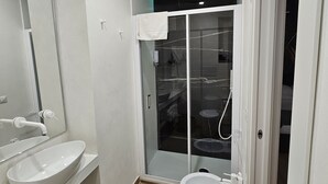 A modern bathroom with a glass-enclosed shower, a white sink, and a toilet. - PALMHOUSE Salerno center with jacuzzi, separate entrance near Metro. (Salerno)