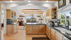 Une cuisine spacieuse avec des meubles en bois, un grand îlot central et une vue sur l’extérieur.