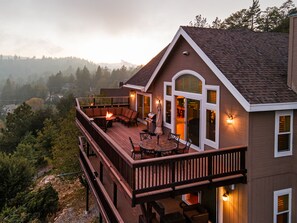 Une maison à deux étages dotée d’une terrasse, d’un espace salon extérieur et d’une cheminée.