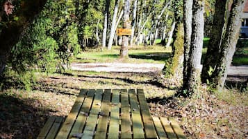 A picnic table in a park with trees and a sign in the background.