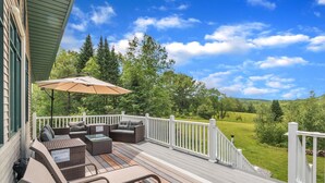 A deck with outdoor furniture, a white railing, and a view of a green landscape. - River Valley Sunset Retreat - Peaceful Getaway Near Sunday River & Bethel/Newry (Rumford)