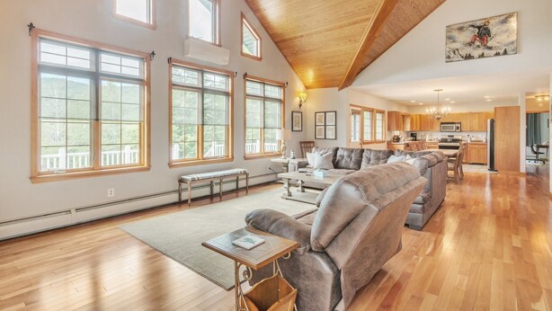A spacious living room with a large sectional sofa, a dining area, and a kitchen.