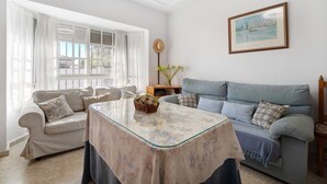 Un salon avec un canapé, une table à plateau en verre et un tableau encadré accroché au mur.