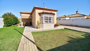 Une maison avec un toit en tuiles, une façade en pierre et une pelouse bien entretenue.