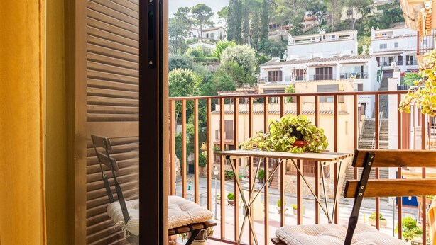A balcony with a table, chairs, and a potted plant.