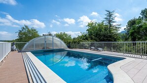 A swimming pool with a glass enclosure, surrounded by a white fence, and trees in the background. - Holiday Home "Horrio" with Mountain View, Shared Pool & Wi-Fi (Querol)