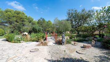 Un jardin avec un sentier en pierre, un pont rouge et une statue.