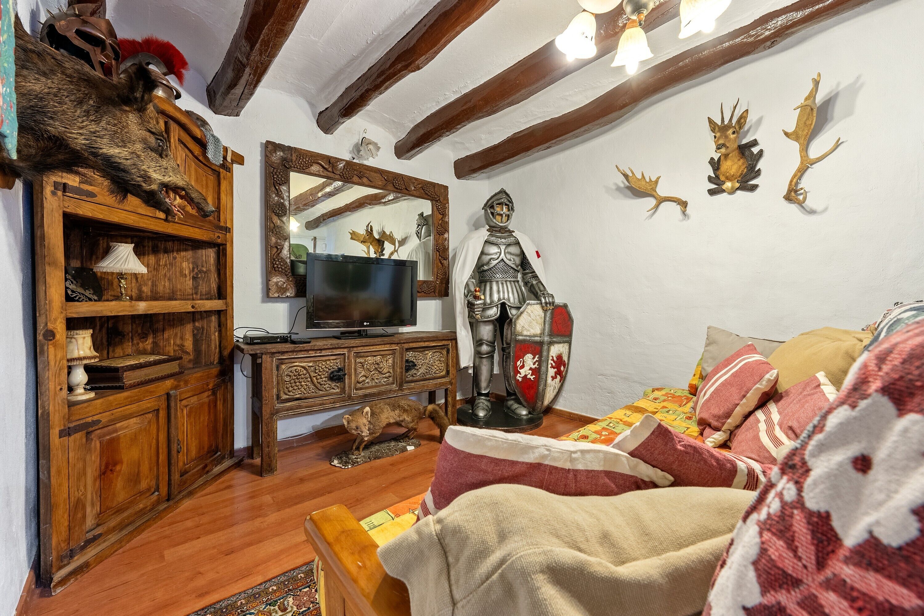 Une pièce comprenant un meuble en bois, un téléviseur, une statue de chevalier décorative et un miroir.