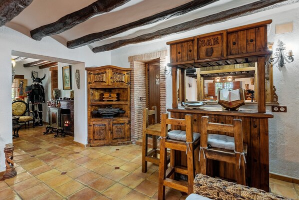A rustic interior with exposed wooden beams, a fireplace, and a bar area with wooden furniture.