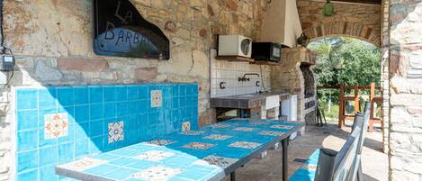 An outdoor seating area with stone walls, a tiled bench, and a sign reading 'LA BARBE.'