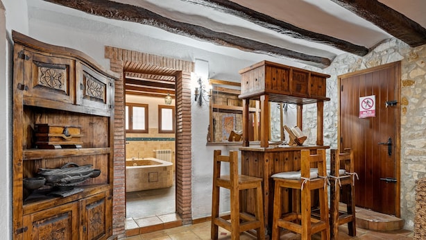 A rustic interior with wooden furniture, a stone wall, and a bathroom visible through an open door. - Chalet "Can Tronc" with Mountain View, Shared Pool & Wi-Fi (Querol)