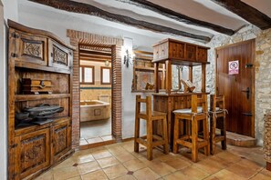 A rustic interior with wooden furniture, a stone wall, and a bathroom visible through an open door.