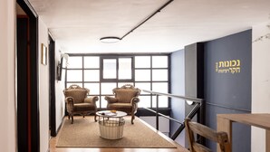 A modern interior with a wooden floor, two armchairs, a small round table, and a large window with a view.